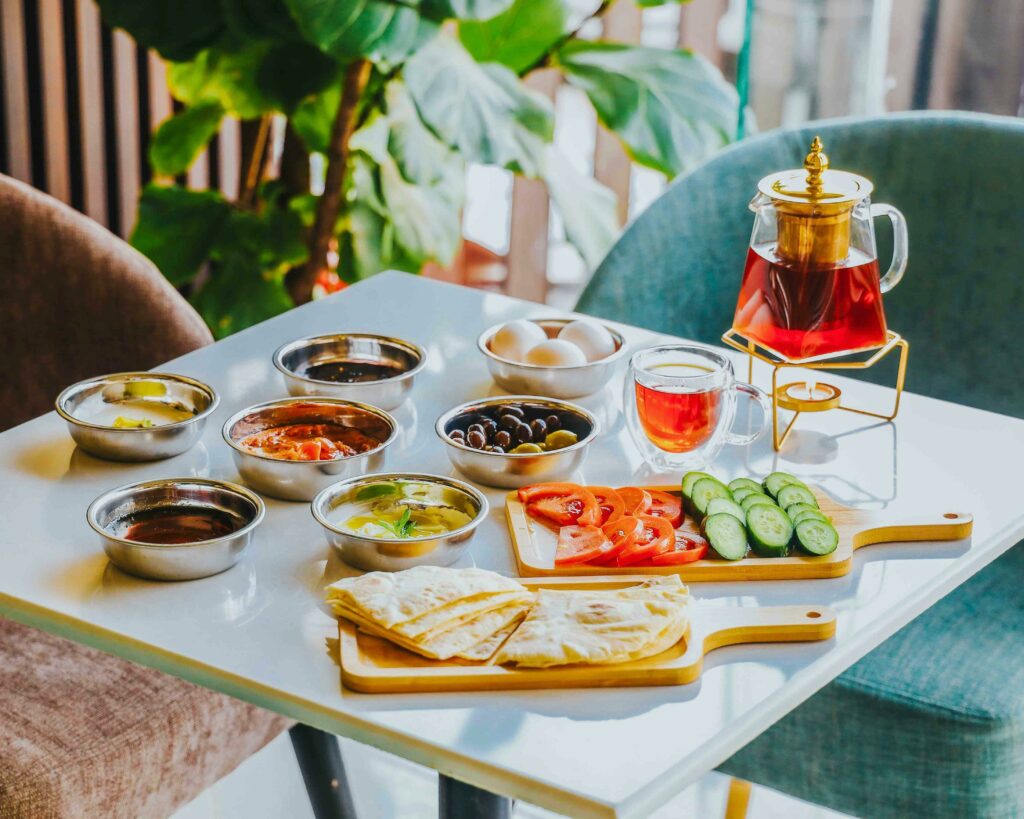A vibrant spread of traditional Arabic breakfast with tea, fresh vegetables, and dips.